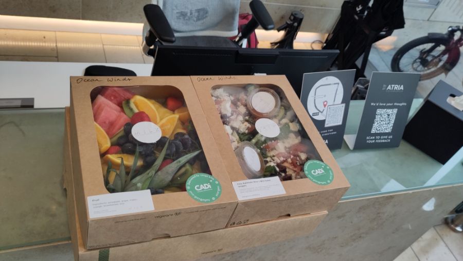 A large meal platter underneath two small platters containing fruit and salad, placed on a counter.