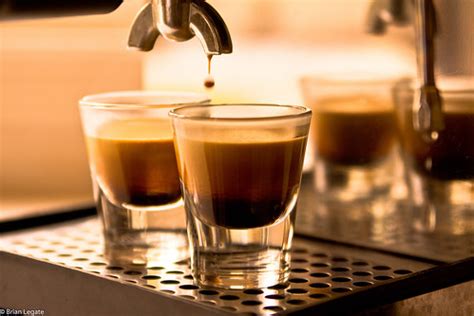 Two espresso glasses that have just been filled by the coffee sitting on the draining board